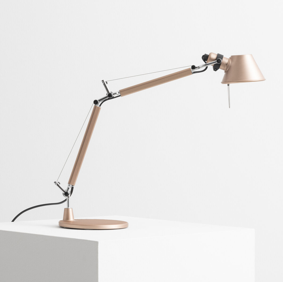 Artemide 'Tolomeo Micro' Schreibtischlampe in Gold auf einem weißen Podest. Die moderne, minimalistische Lampe hat ein schlankes, einstellbares Design mit mehreren Gelenken und einer schlanken, runden Basis.