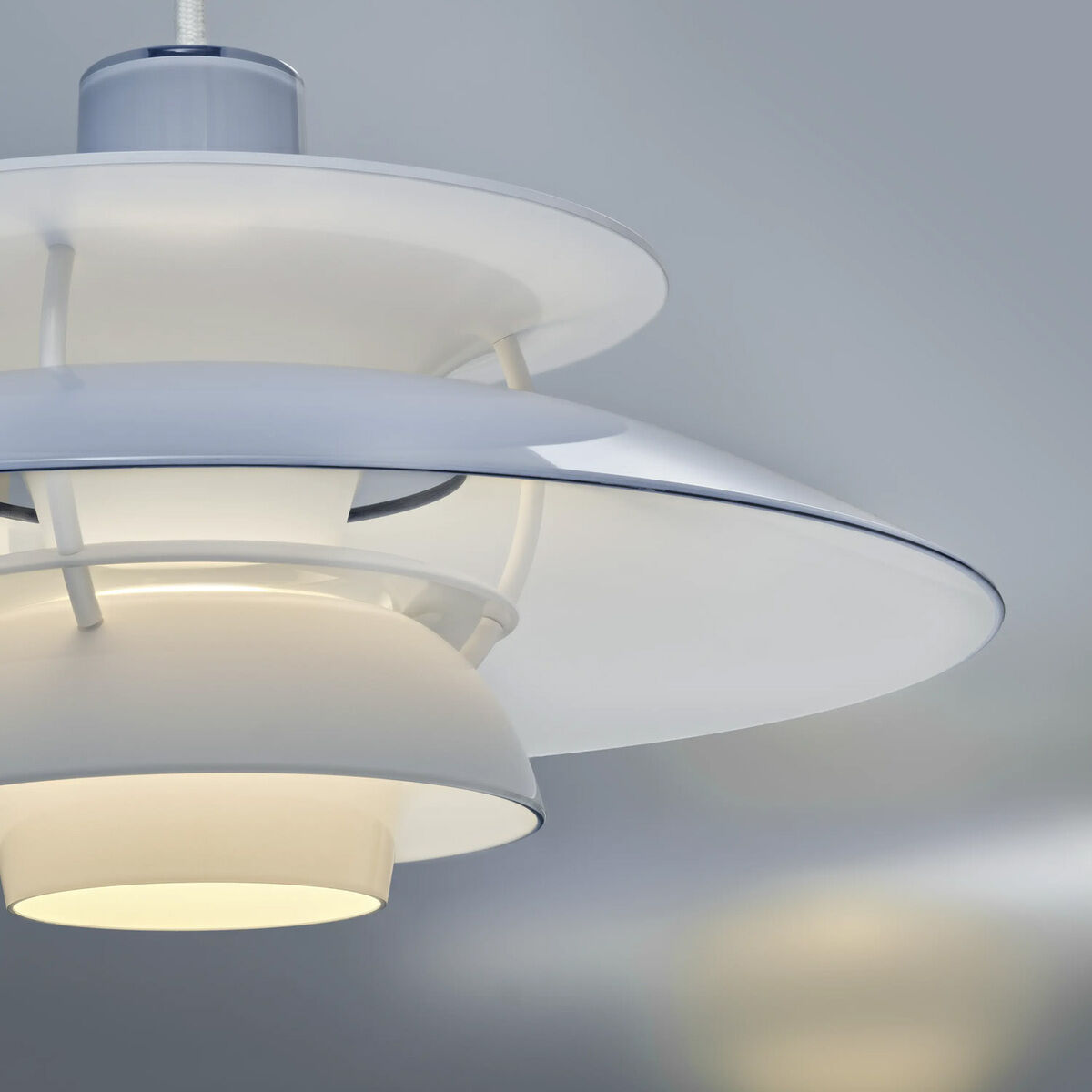 Detailansicht der Hängeleuchte »PH 5 320« von Louis Poulsen. Charakteristisches dreistufiges Schirmsystem aus glänzendem, pulverbeschichtetem Polymer in Weiß, Beige und Blassblau. Die Lampe erzeugt ein blendfreies, weiches Licht. Modernes skandinavisches Design.