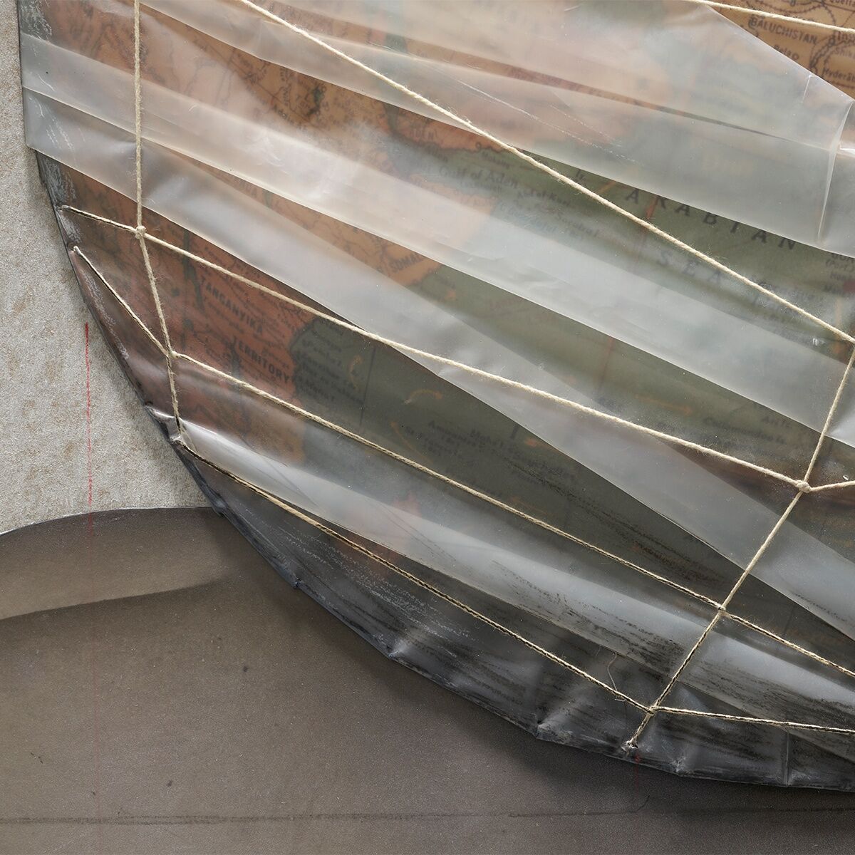 Christo »Wrapped Globe«, limitierte Edition. Nahaufnahme eines kunstvoll verpackten Globus, der in goldfarbenem Stoff gehüllt ist. Die Texturen und Details der Verpackung sind deutlich sichtbar.