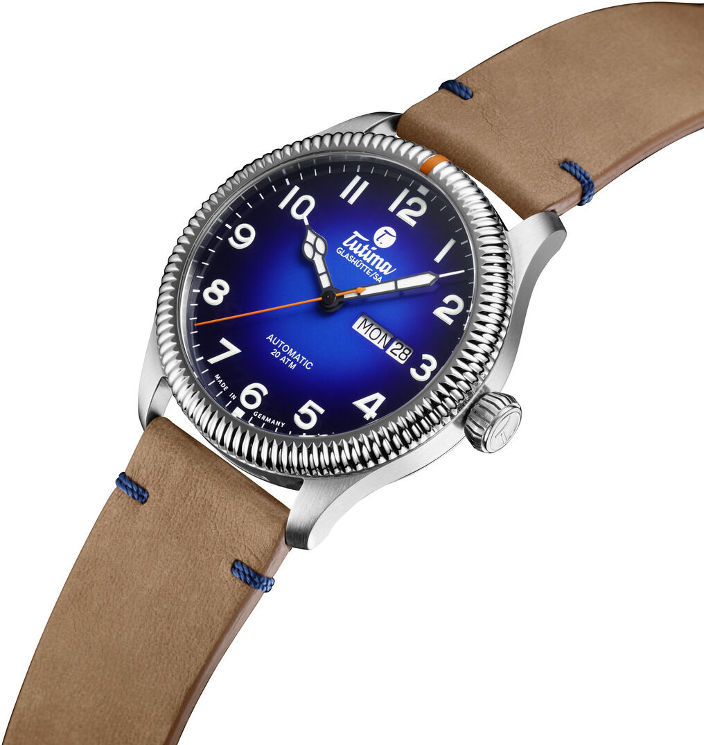 Die Armbanduhr ZEIT-Sonderedition "Grand Flieger Classic Automatic" von Tutima Glashütte zeigt ein blaues Zifferblatt mit klaren weißen Ziffern, silbernem Edelstahlgehäuse, hellbraunem Lederarmband und geriffelter Lünette, seitlich schräg fotografiert.