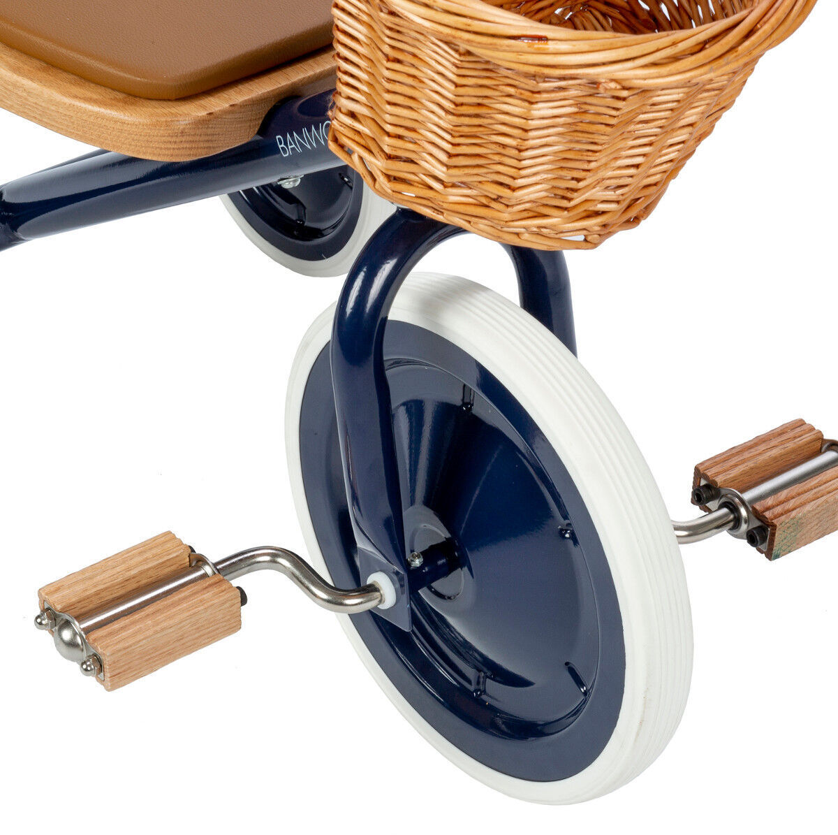 Nahaufnahme eines Retro-Dreirads mit Holzsitz und Metallrahmen. Das Dreirad hat weiße Reifen und Pedale mit Holzgriffen sowie einen geflochtenen Korb.