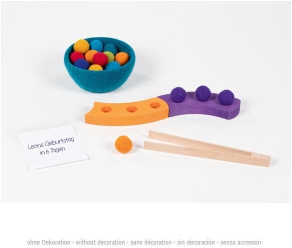 Farbsortierspiel und Adventsspirale aus Holz mit bunten Kugeln in einer Schale und einer hölzernen Spiralbahn. Dazu gehört ein Paar Holzpinzetten. Ein handgeschriebener Zettel liegt daneben. Die Farben sind orange, gelb, lila, blau und rot.