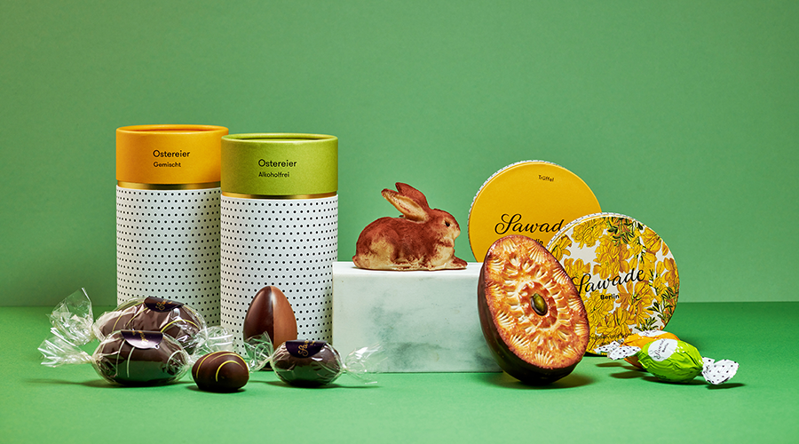 Zwei Geschenksets mit Ostereier-Gummibärchen und alkoholfreien Ostereiern, Schokoladenhasen und runden Keksen mit 'Sawade' Schriftzug
