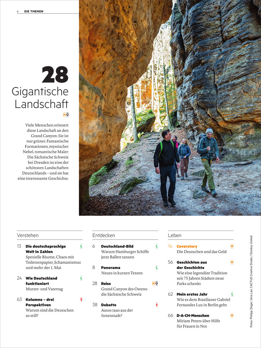 Titelseite des Magazins 'Deutsch perfekt 6/2026' von Spotlight Verlag. Großes Foto zeigt vier Wanderer in outdoor Kleidung in einer felsigen, bewaldeten Landschaft. Links Text: '28 Gigantische Landschaft', kurze Einführung zum Schwerpunktthema und Inhaltsübersicht.