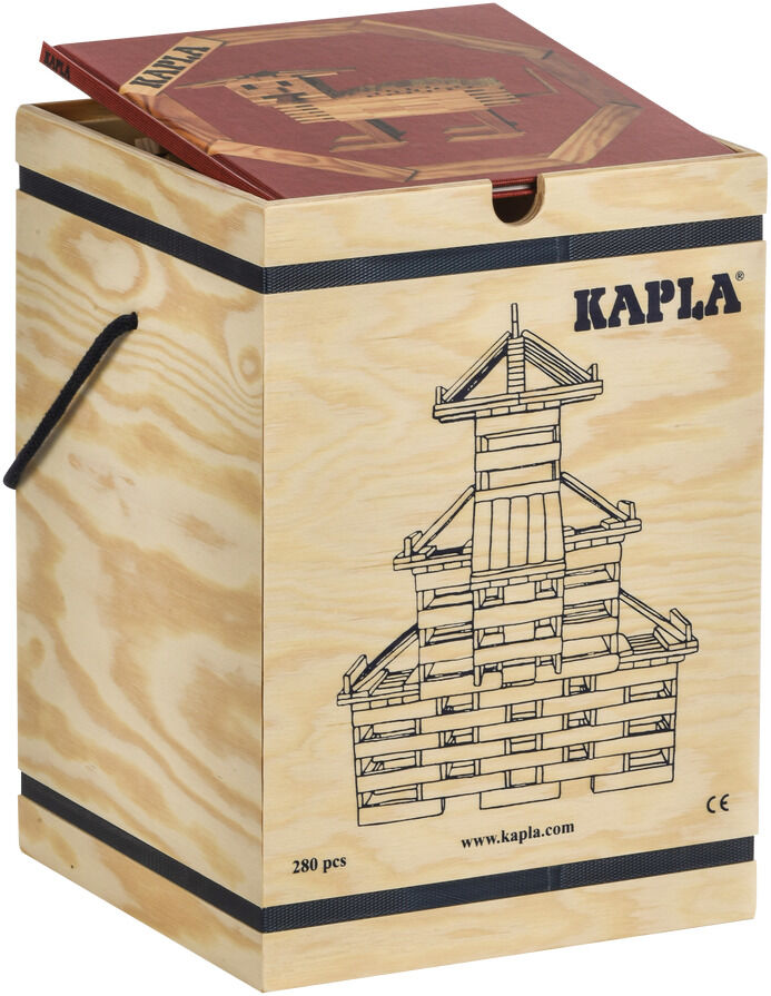 Holzkasten mit schwarzen Griffen und einer Zeichnung einer Holzstruktur auf der Seite. Obenauf liegt ein rot-braunes Buch. Auf dem Kasten steht 'Kapla' und er enthält 280 Holzbausteine.