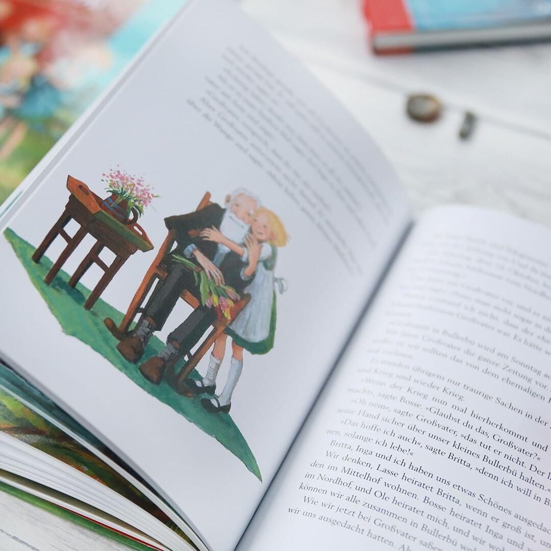 Offenes Buch mit einer farbenfrohen Illustration, die ein Mädchen und einen Jungen zeigt. Der Hintergrund des Bildes ist verschwommen, zeigt jedoch weitere Bücher.