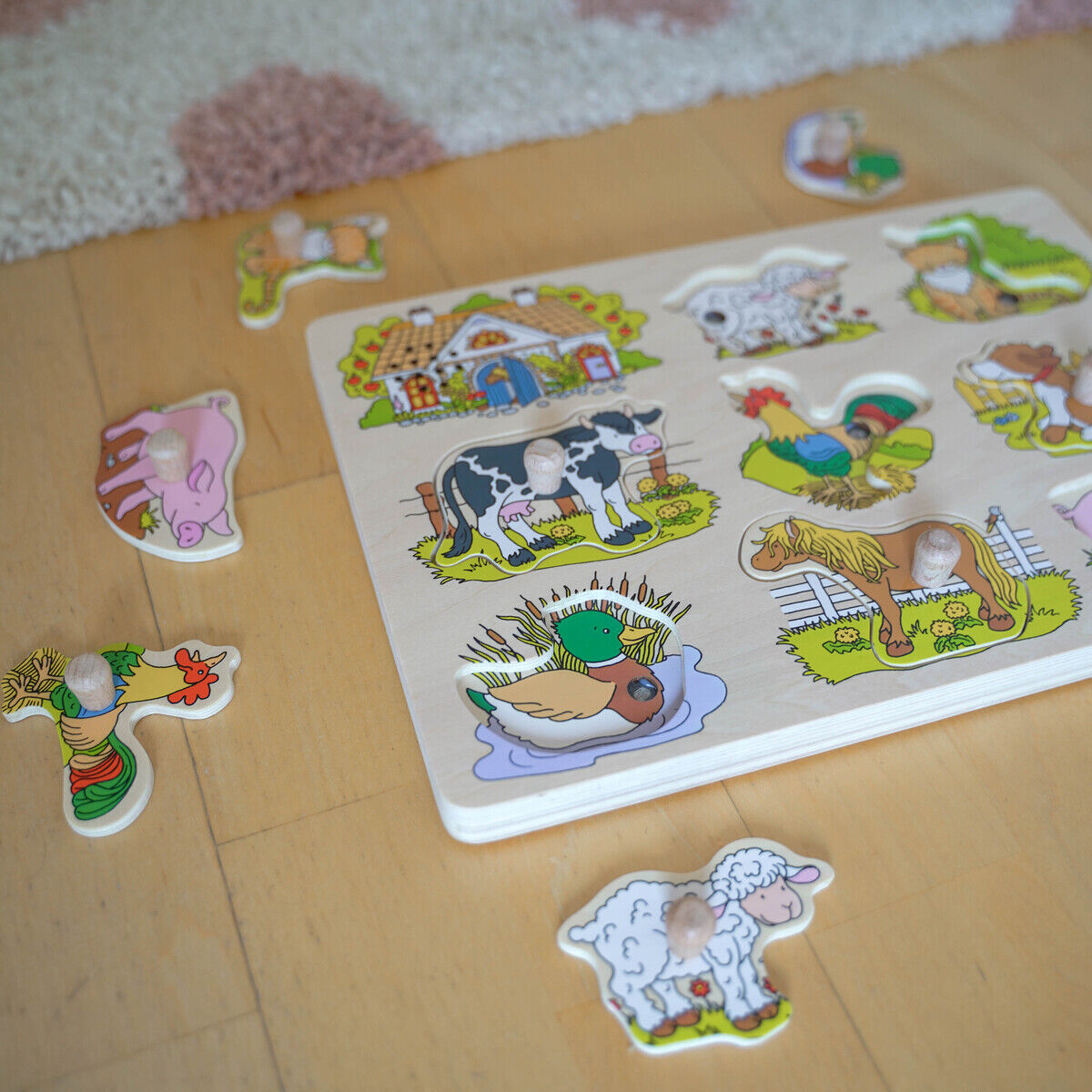 Holz-Soundpuzzle mit Bauernhof-Motiven und Tierstimmen, mehrere herausnehmbare Puzzleteile mit Abbildungen von Bauernhoftieren wie Kuh, Ente, Schwein und Schaf, auf hellem Holzboden liegend mit teilweise gelöstem Puzzle.