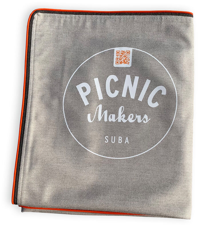Eine graue Picknickdecke namens »Squarepark 11« mit einem weißen runden Logo, das die Wörter 'PICNIC Makers SUBA' enthält. Die Decke hat orangefarbene Akzente an den Rändern.
