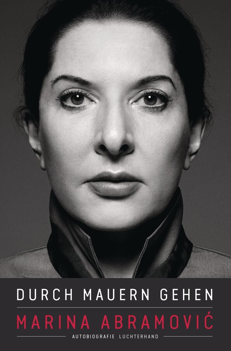 Buchcover von 'Durch Mauern Gehen' von Marina Abramovic. Schwarz-Weiß-Porträt der Künstlerin mit ernstem Gesichtsausdruck, schwarzer Hintergrund. Buchtitel in Weiß und Rot.