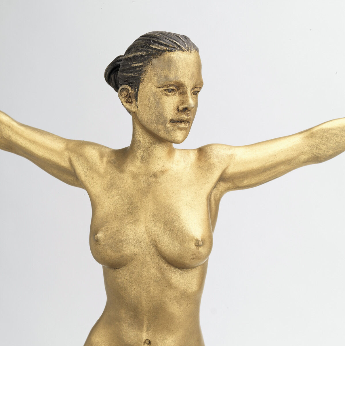 Eine goldene Skulptur einer nackten, stehenden Frau mit ausgebreiteten Armen, die den Eindruck von Freiheit vermittelt. Die Skulptur, erstellt von Leo Wirth im Jahr 2021, hat eine glatte und metallische Oberfläche.