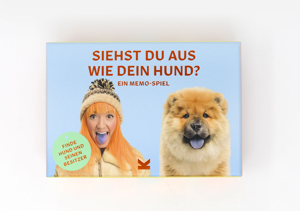 Eine Spielschachtel mit dem Titel 'Siehst du aus wie dein Hund?' zeigt eine Frau mit orangen Haaren und einem Hund, die beide die Zunge herausstrecken. Das Spiel lädt dazu ein, Hunde ihren Besitzern zuzuordnen.