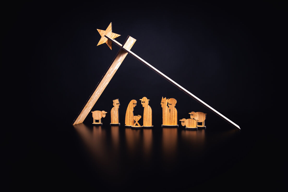 Eine minimalistische Krippe aus Holz mit sternenüberspanntem Dach und Figuren der Heiligen Familie und Tieren vor schwarzem Hintergrund.