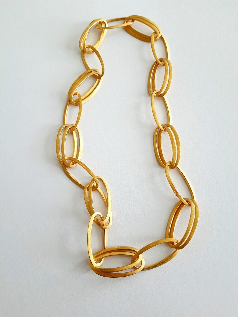 Das Bild zeigt eine goldene Halskette mit ovalen Gliedern auf einem weißen Hintergrund. Die Kette wirkt elegant und hochwertig.