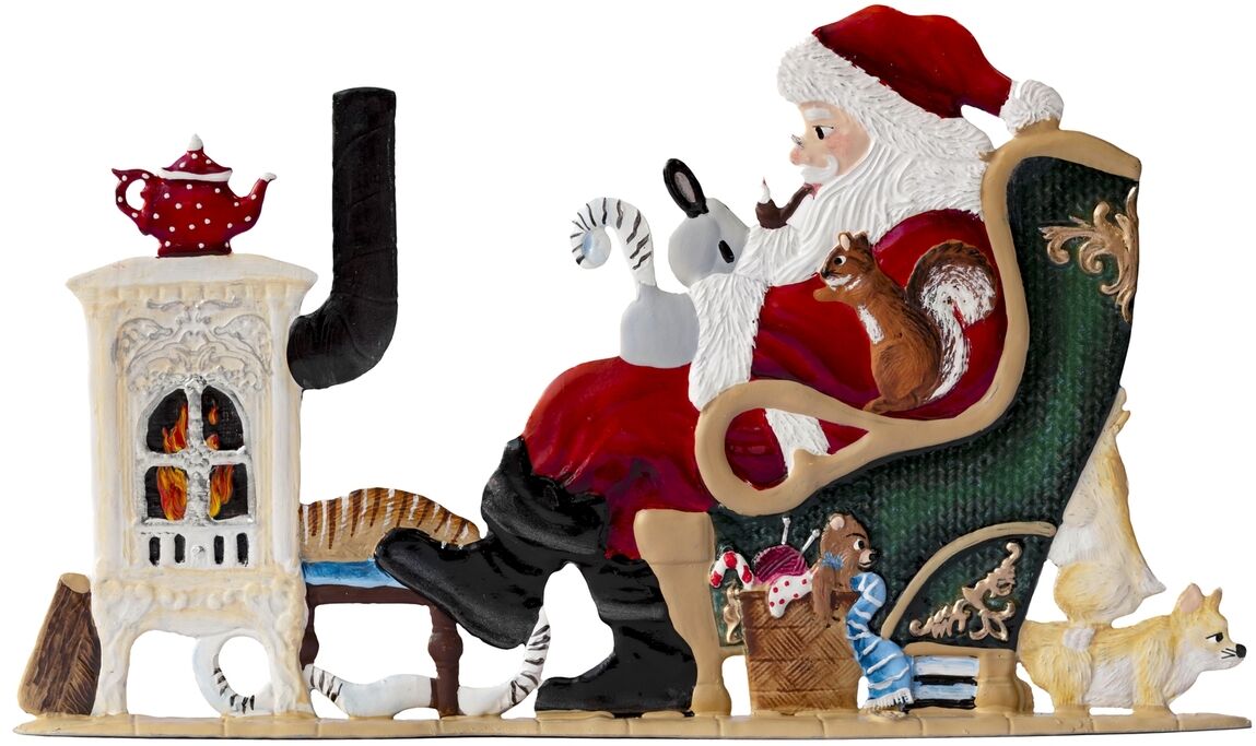 Detailreich bemalte Zinnfigur mit dem Weihnachtsmann auf einem grünen Sessel sitzend, Wunschliste schreibend, vor einem weißen Kamin mit brennendem Feuer; umgeben von Geschenken, Tieren und winterlichem Spielzeug – weihnachtliche und festliche Dekoration.