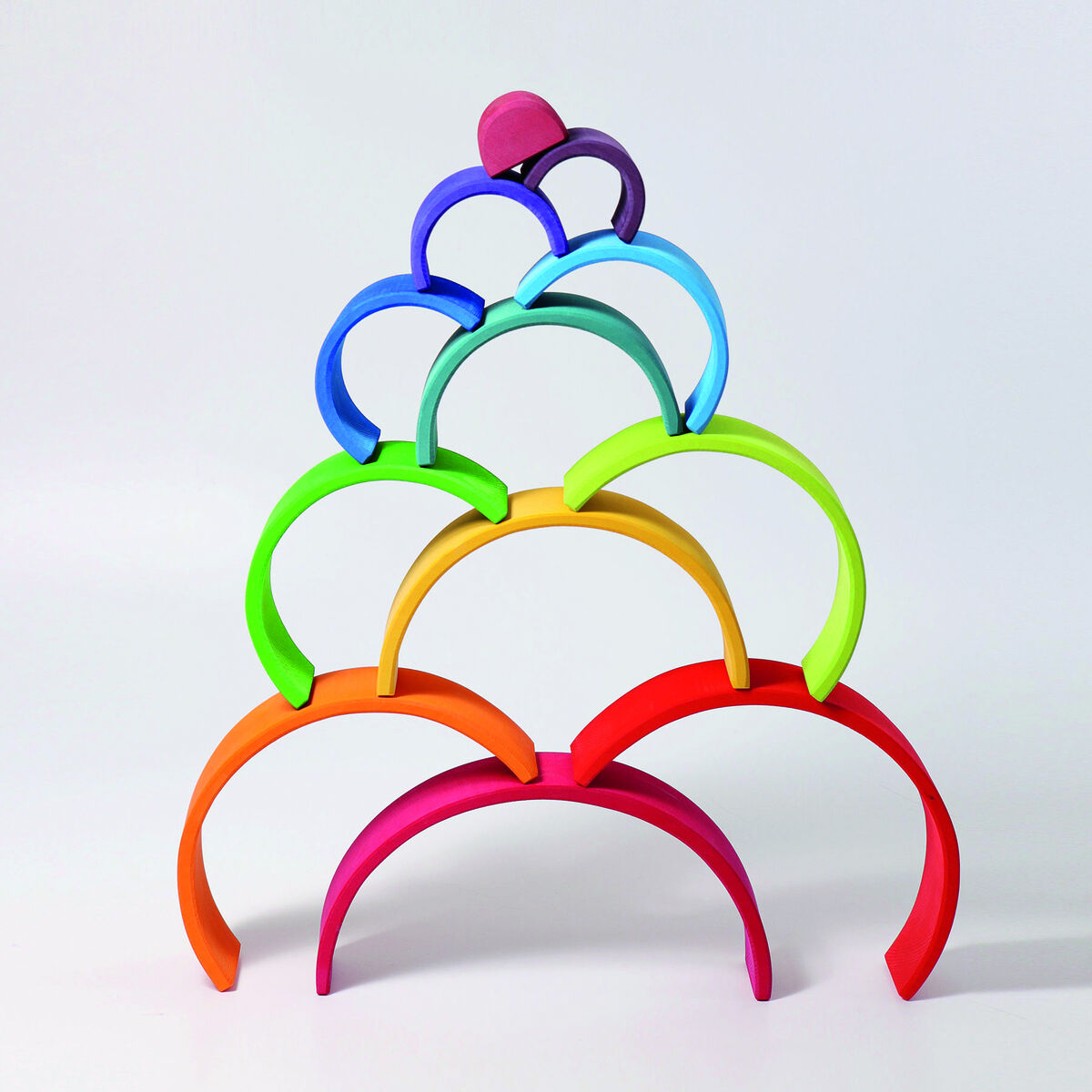 Regenbogen Holzspielzeug bestehend aus mehreren bunten, halbkreisförmigen Bausteinen ist zu einer pyramidenartigen Struktur aufgestapelt.