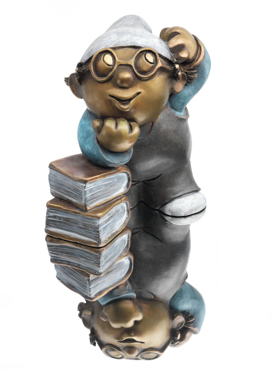 Bronzefigur eines Mainzelmännchen-Charakters unter dem Titel 'Det, der Denker'. Die Figur trägt eine Brille, ein blaues Oberteil und steht auf einer Ansammlung von Büchern. Der Charakter hat einen nachdenklichen Ausdruck und stützt seinen Kopf auf seine linke Hand.