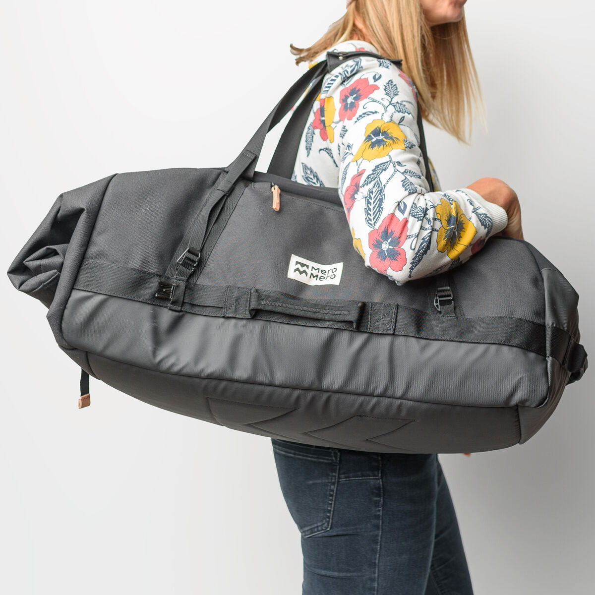 Eine Frau trägt eine große, schwarzen Duffle Bag »Smögen«, eine vielseitige und praktische Tasche mit verstellbaren Schultergurten. Die Tasche ist einfach zu tragen und bietet viel Stauraum, ideal für Reisen, Sport oder Outdoor-Aktivitäten.