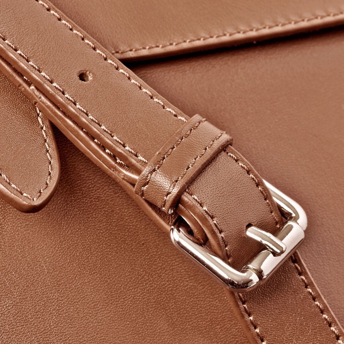 Nahaufnahme einer braunen Leder-Umhängetasche mit silberner Schnalle. Die Tasche hat einen stilvollen und eleganten Look, ideal für den täglichen Gebrauch und verschiedene Anlässe.