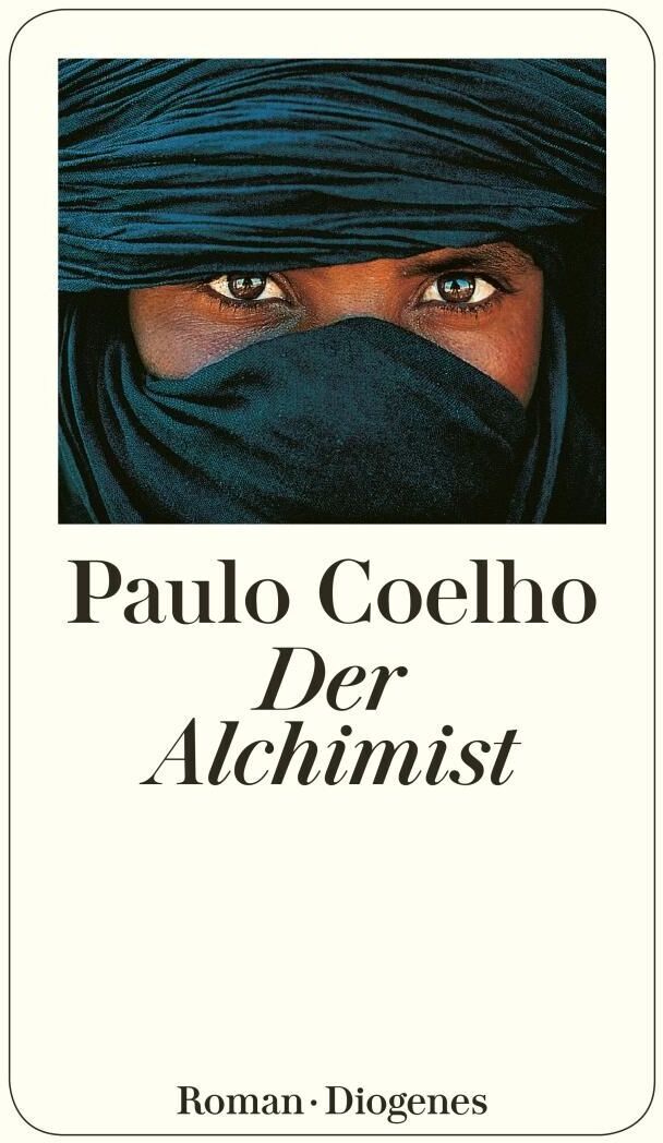 Das Buch 'Der Alchimist' von Paulo Coelho zeigt auf dem Cover das Gesicht einer Person in einem blauen Kopftuch, die Augen sind sichtbar. Der Hintergrund ist beige, und der Titel sowie der Autorenname sind in Schwarz geschrieben. Unten steht 'Roman' und 'Diogenes'.