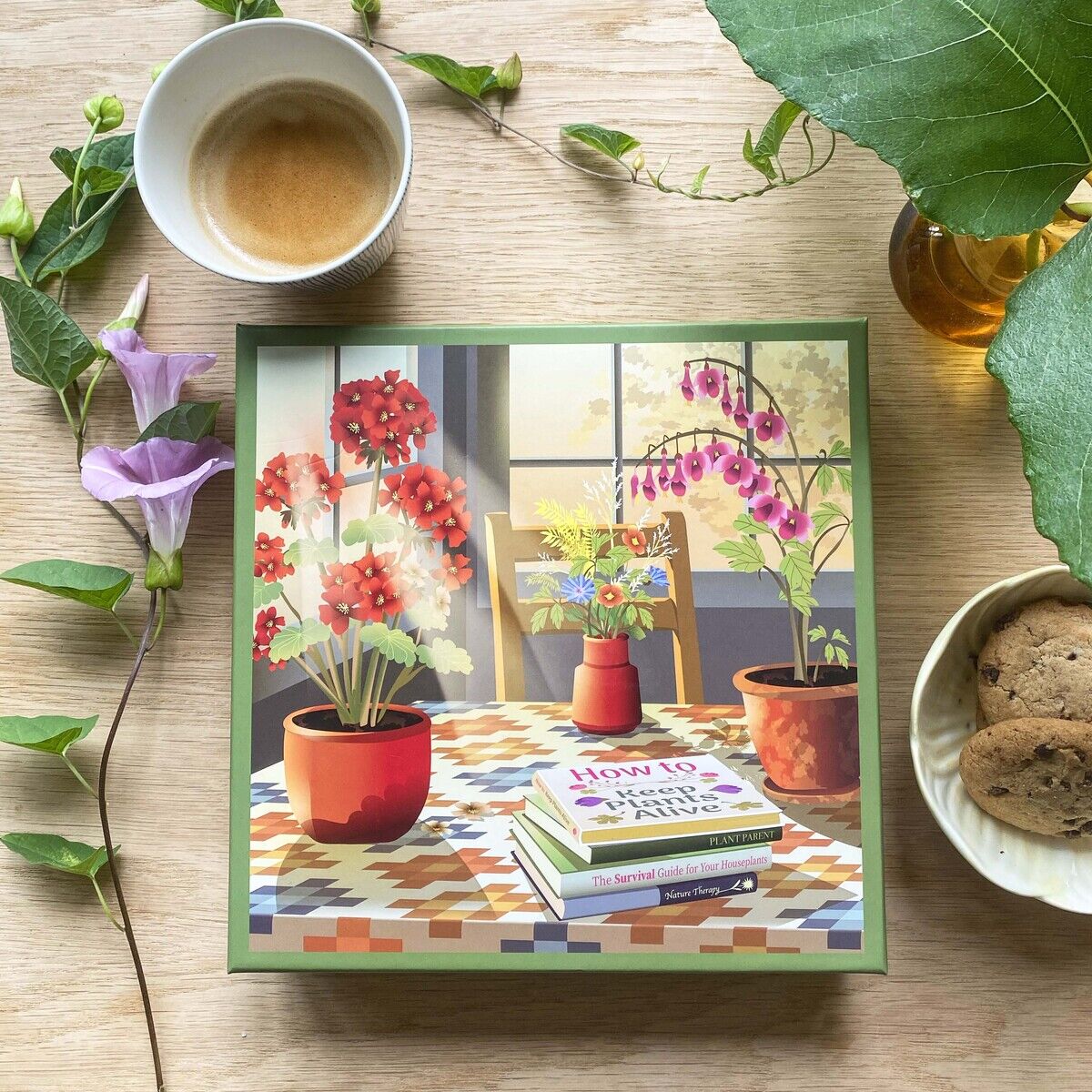 Das Bild zeigt das 500 Teile Puzzle »Blossom« von VISSEVASSE. Auf dem Cover sind Blumentöpfe mit roten, weißen und pinken Blüten auf einem Tisch vor einem Fenster abgebildet. Umgeben ist das Puzzle von einer Tasse mit Getränkeresten, Keksen, einem Blatt und Blumen.