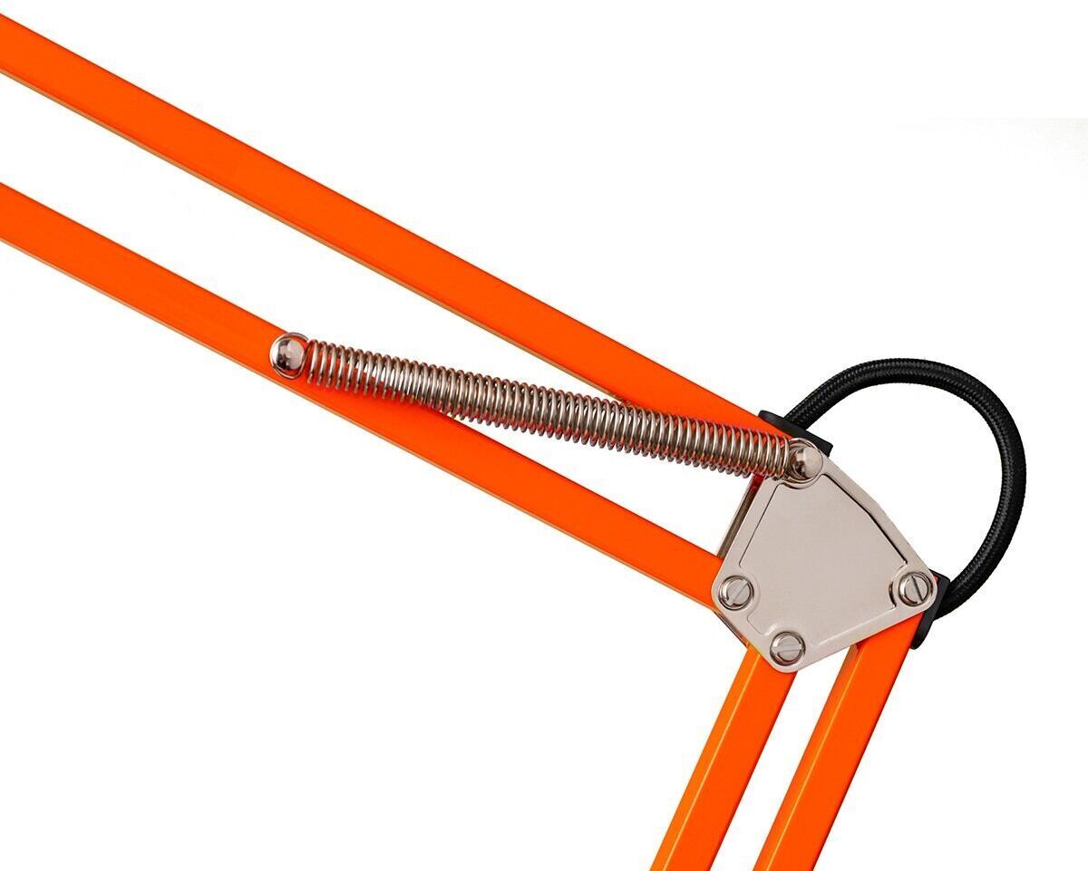Nahaufnahme einer Tischleuchte mit Federzug und Klemmfuß in der ZEIT-Sonderedition. Die Lampe zeigt ein verstellbares, orangenes Gestell mit einer silbernen Feder und einem schwarzen Kabel.