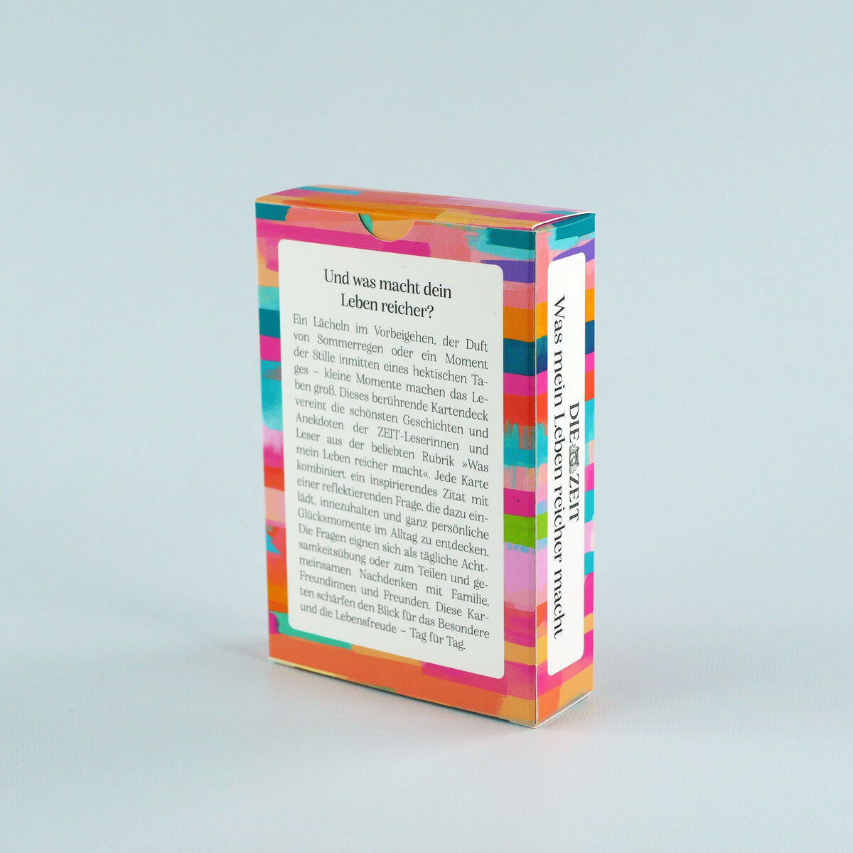 Abgebildet ist eine bunt gestaltete Schachtel des Inspirationskartensets »Was mein Leben reicher macht« von DIE ZEIT, Münchner Verlagsgruppe. Die Rückseite informiert über Inhalt und Einsatzmöglichkeiten der Achtsamkeitskarten für mehr Glücksmomente im Alltag.