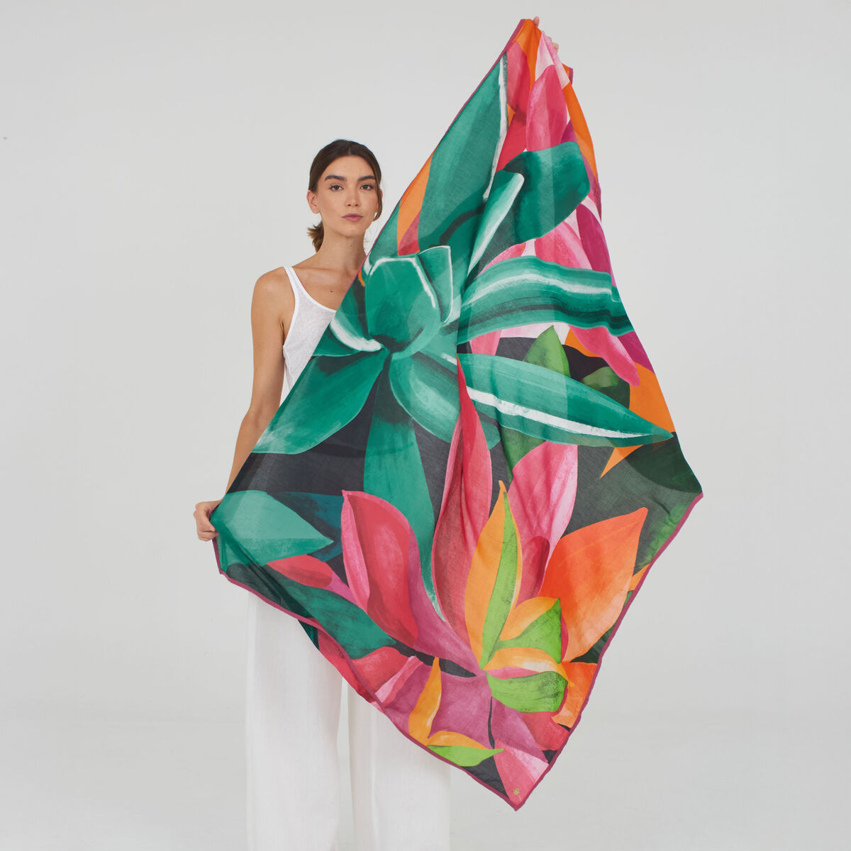 Der Schal „Cassey“ von Shalls Barcelona liegt locker drapiert auf heller Fläche. Er besteht aus leicht transparentem, weichem Gewebe, überwiegend orange mit weißen Akzenten. Feine, natürliche Fasern sorgen für einen edlen, sanften Glanz. Das Tuch wirkt luxuriös und elegant.