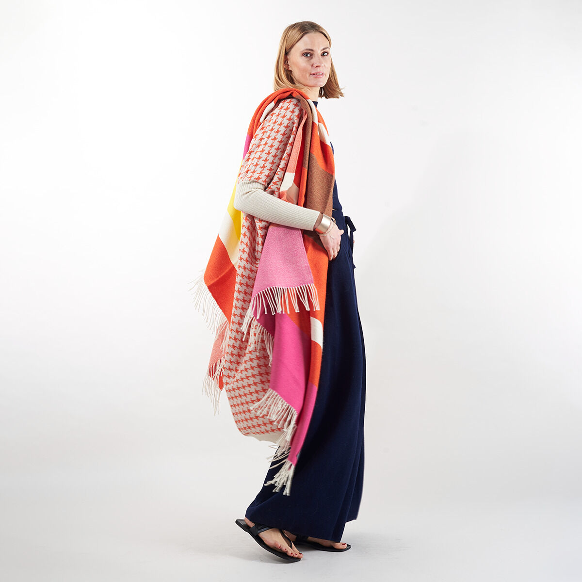 Frau trägt ein elegantes Cape der ZEIT-Jubiläumsedition »Surya«, welches in Rosa, Orange, Gelb, Weiß und Blau gestaltet ist. Perfekt für kalte Tage.