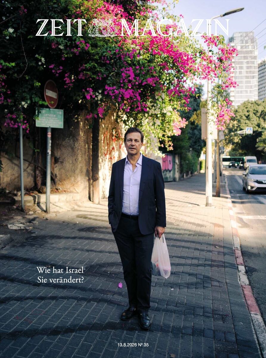 Titelbild des ZEIT Magazins 35/2026: Ein Mann im Anzug steht auf einem Gehweg in urbaner Umgebung mit Blütenbüschen und Lichtschatten. Im Hintergrund Pflanzen, Straßenschilder und Hochhäuser. Text: „Wie hat Israel Sie verändert?“ Datum: 13.8.2026 Nr. 35.