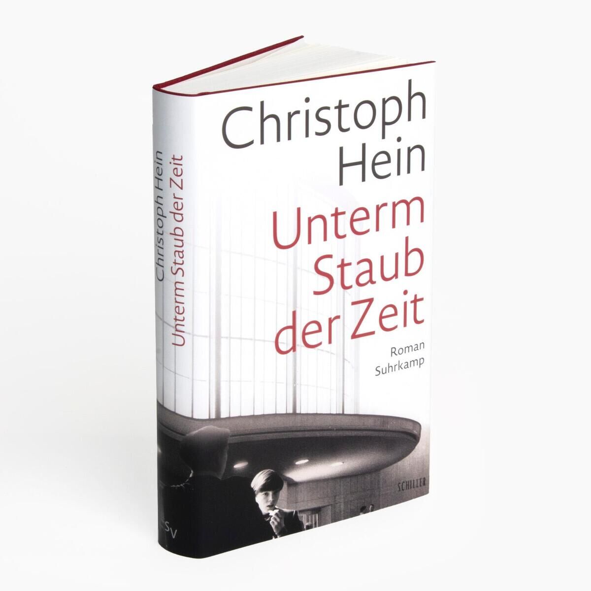 Buchcover von 'Christoph Hein - Unterm Staub der Zeit'. Das Cover zeigt den Titel des Buches in roter und schwarzer Schrift auf weißem Hintergrund, mit einer Schwarz-Weiß-Fotografie im unteren Bereich.