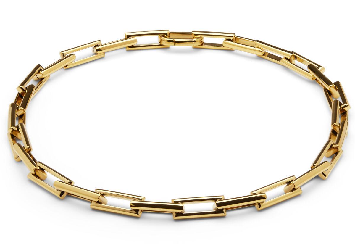 Abgebildet ist ein modernes Collier namens »Traverse« aus goldfarbenem Metall mit rechteckigen, ineinandergreifenden Gliedern. Die Kette liegt kreisförmig auf weißem Hintergrund und besitzt ein zeitlos elegantes Design, das als stilvolles Schmuckstück für verschiedene Anlässe geeignet ist.