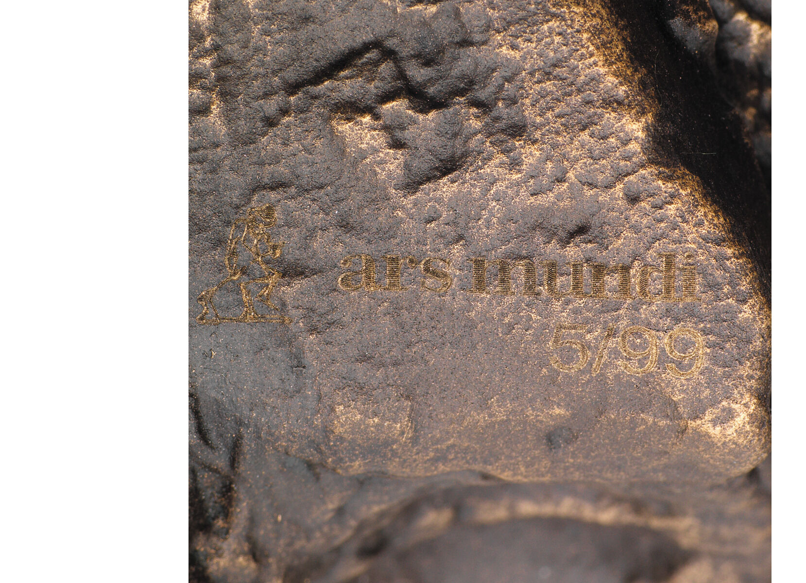 Eine Bronzeskulptur mit dunklen Brauntönen und goldenen Details. In die Oberfläche ist die Aufschrift 'ars mundi 57/99' eingraviert. Die Skulptur ist ein künstlerisches Werk von Christoph Fischer mit dem Titel 'Der Gedanke'.