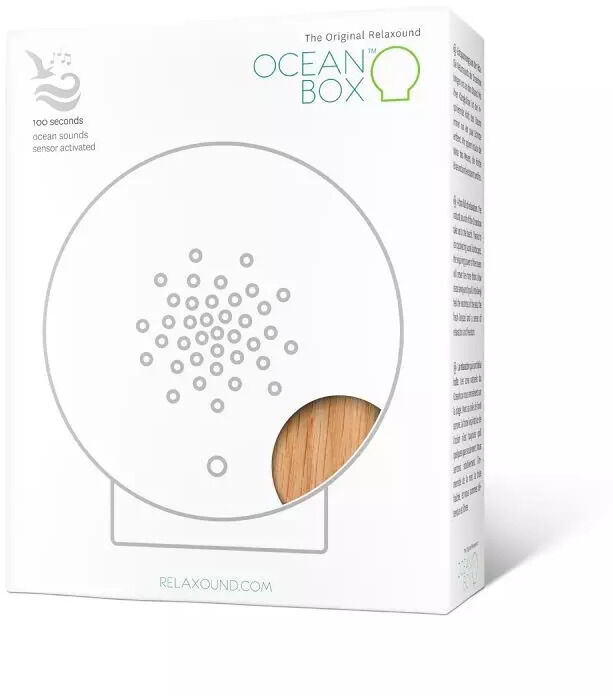 Oceanbox, ein geometrisch geformtes Entspannungsgerät mit einem minimalistischen Design, präsentiert in einer Verpackung mit Holzoptik und dezenten Farben. Das Gerät ist geeignet für entspannende Klang- und Aromatherapie.