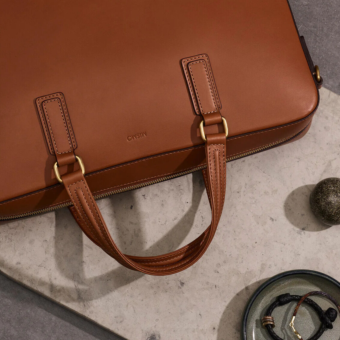 Businesstasche »MORRIS« in Naturbraun aus Leder, mit goldfarbenen Metalldetails und einem robusten Tragegriff. Geeignet für berufliche Anlässe und modische Alltagsmomente.