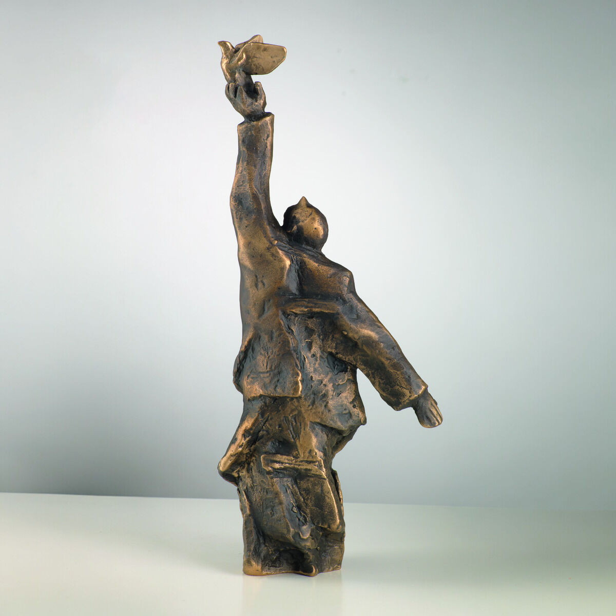 Die Skulptur 'Der Gedanke' von Christoph Fischer, aus dem Jahr 2023, zeigt eine menschliche Figur in einer dynamischen Pose. Sie besteht aus bronzefarbenem Material und steht aufrecht mit einem erhobenen Arm, als ob sie etwas in der Hand hält. Die Skulptur ist modern und hat abstrakte, weiche Formen.