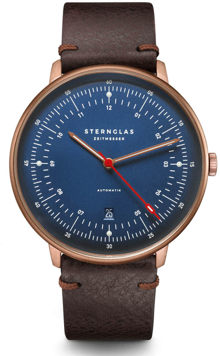ZEIT-Sonderedition Uhr 'Hamburg' in Bronze. Diese schicke Armbanduhr hat ein blaues Zifferblatt, ein braunes Lederarmband und ein Bronzegehäuse. Weitere Details umfassen weiße Stundenmarkierungen und eine Datumsanzeige.