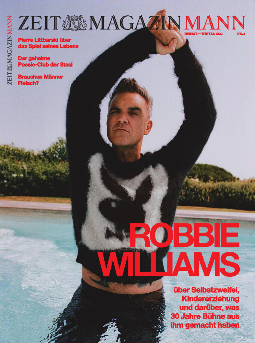 Cover des ZEITmagazin MANN Ausgabe 2/22 mit einem Foto von Robbie Williams in einem schwarzem Pullover mit weißem Muster, der am Pool posiert. Der Titel ist in roten und schwarzen Buchstaben geschrieben.