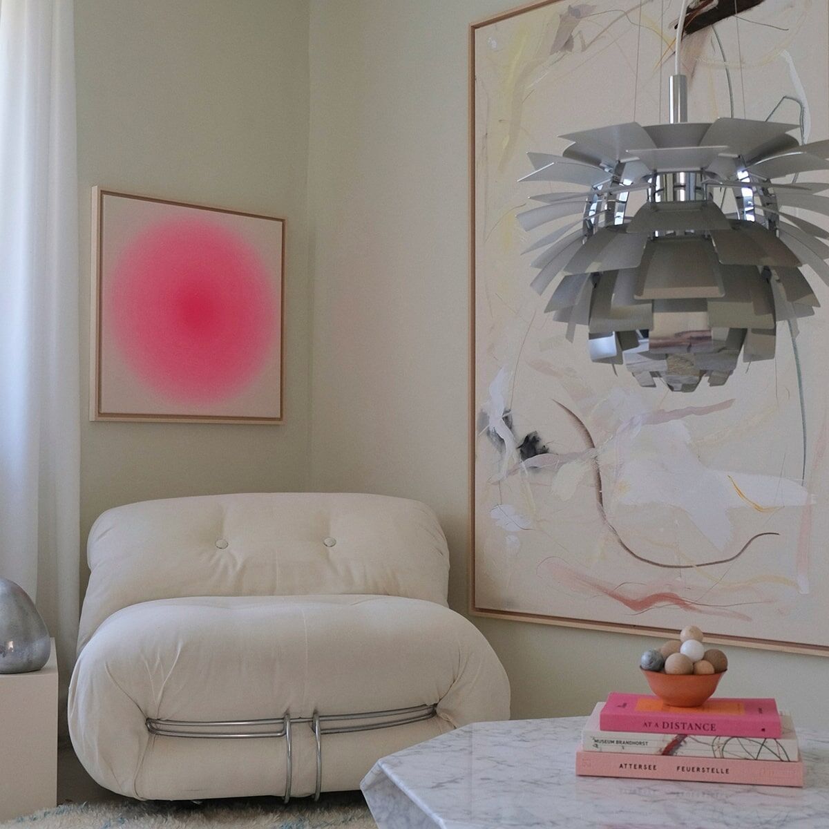 Ein modernes Wohnzimmer mit einem kunstvollen Kunstdruck der ZEIT-Sonderedition Sorbet in Pink an der Wand. Das Bild hat einen farbverlaufenden pinken Kreis. Der Raum ist mit einer hellen Lounge Couch, einem weißen Teppich und einer großen Pendelleuchte eingerichtet.