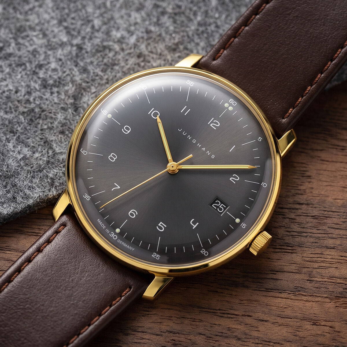 Die ZEIT-Sonderedition »max bill Quarz« von Junghans zeigt ein anthrazit-braunes Zifferblatt mit Sonnenschliff, goldfarbenem Gehäuse und dunkelbraunem Lederarmband. Der gelbgoldene Sekundenzeiger und das sphärisch gewölbte Saphirglas verleihen einen zeitlos-eleganten Eindruck.