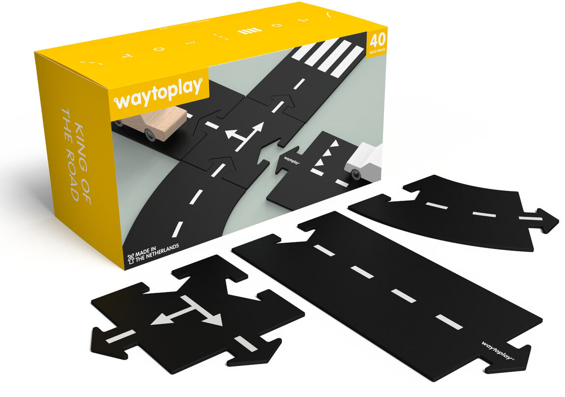 Das Bild zeigt das Straßenbau-Set »King of the road« von waytoplay. Im Vordergrund liegen schwarze, flexibel verbundene Straßenteile mit weißen Markierungen, während im Hintergrund eine gelbe Verpackung mit Produktabbildung und einem kleinen Holzauto zu sehen ist. Das Set besteht aus mehreren Verbindungsteilen, bietet kreative Möglichkeiten für Kinder und ist für fantasievolles Spielen geeignet.