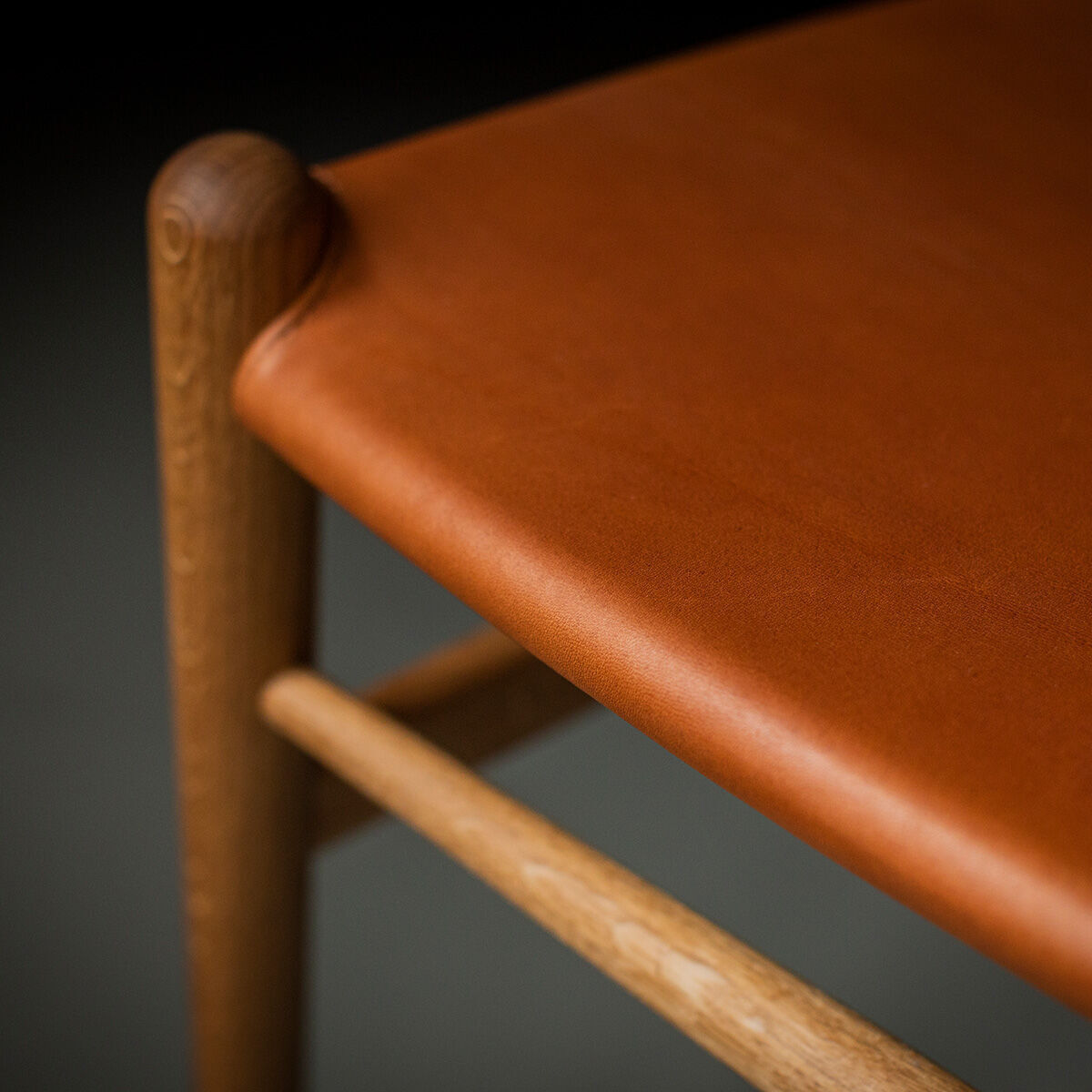 Nahaufnahme des ZEIT Sonderedition »CH24« Wishbone Chairs aus Eiche und Leder, mit Fokus auf Sitzfläche und Armlehne.