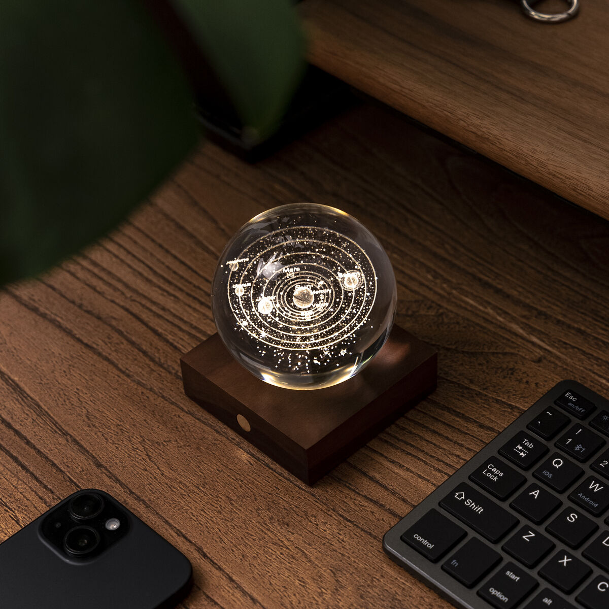 Auf einem hochwertigen Sockel aus dunkelbraunem Walnussholz ruht eine kunstvoll gearbeitete, transparente Kristallkugel mit Sonnensystem-3D-Lasergravur. Über einen eleganten Kupferknopf wird das Bernsteinlicht in drei Helligkeitsstufen reguliert und taucht die Szene in warmes, sanftes Licht.