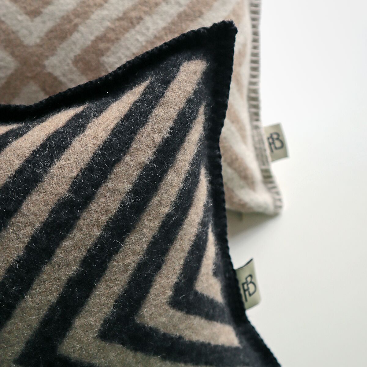 Kaschmir Kissenbezug »Pontresina« mit einem diagonalen Streifenmuster in den Farben Beige und Schwarz, dekorativ und luxuriös auf einem weißen Hintergrund.