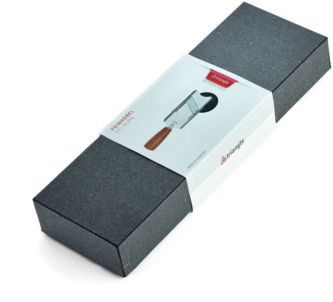 Feinhobel ‚Soul‘ aus Pflaume in einer grauen Schachtel mit weißem Etikett. Der Hobel hat einen Edelstahlkörper und einen Holzgriff.
