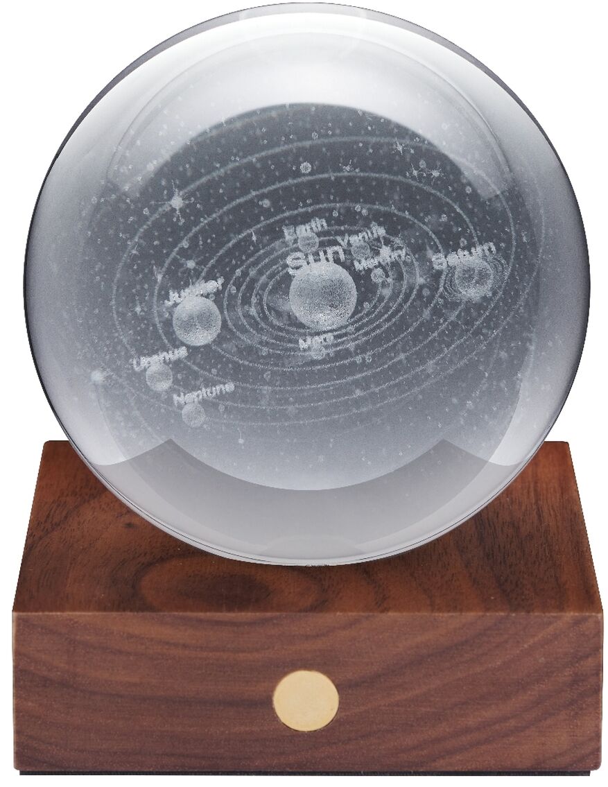 Auf einem massiven, dunkelbraunen Sockel aus Walnussholz sitzt eine klare, runde Kristallkugel mit 3D-Lasergravur des Sonnensystems. Ein goldfarbener Touch-Knopf ist an der Vorderseite des Sockels sichtbar. Die Lampe wirkt hochwertig und minimalistisch.