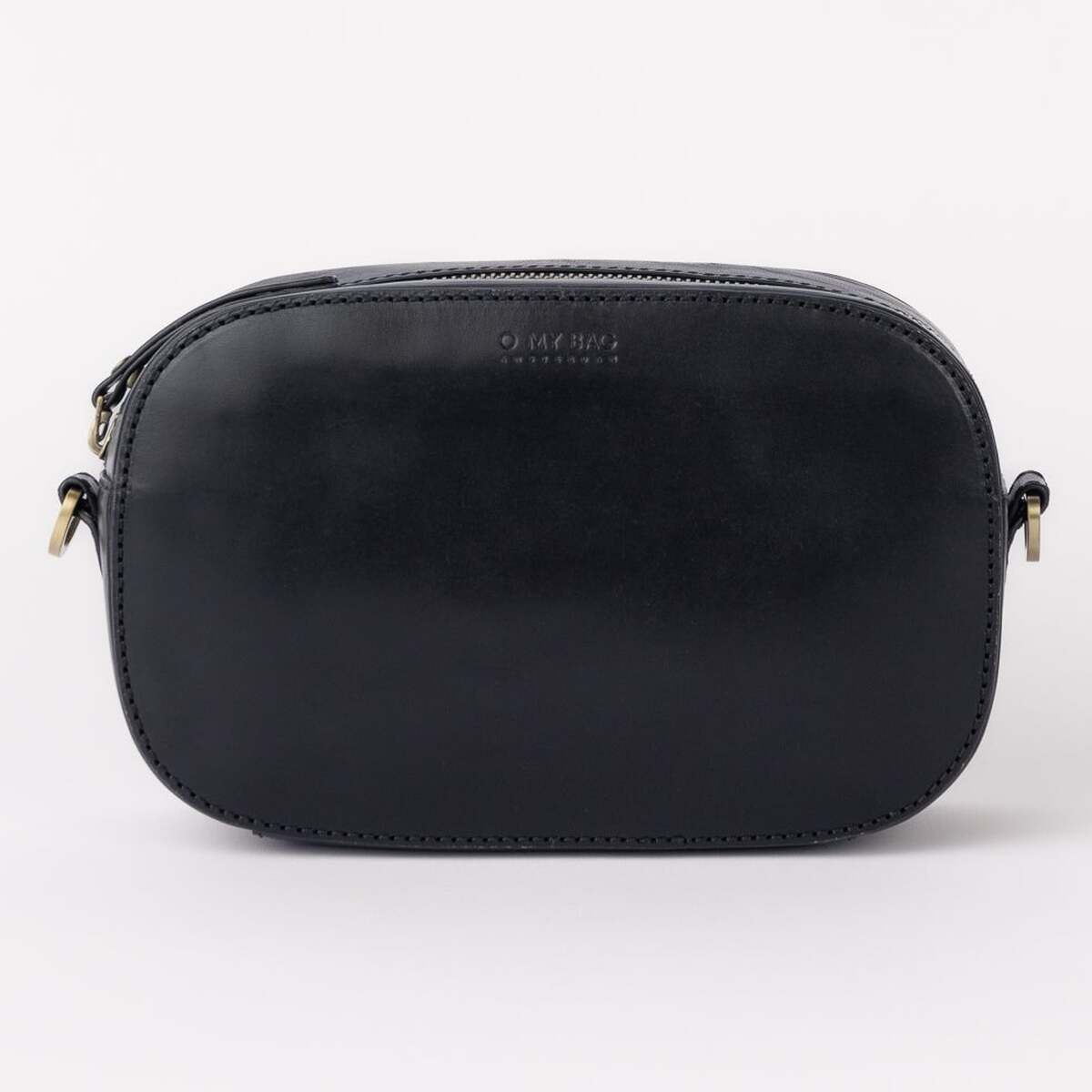 Die Abbildung zeigt eine schlichte schwarze Umhängetasche aus Leder mit abgerundeten Ecken und minimalistischen Details. Die Tasche steht vor einem hellen Hintergrund, die Metallteile sind dezent und die Form ist kompakt und elegant.