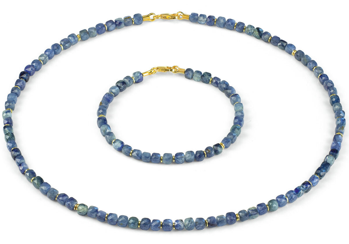 Das Bild zeigt ein Schmuckset bestehend aus einer Halskette und einem Armband aus kleinen, würfelförmigen blauen Perlen mit goldenen Zwischenelementen, auf weißem Hintergrund angeordnet. Das Set wirkt elegant und modern.