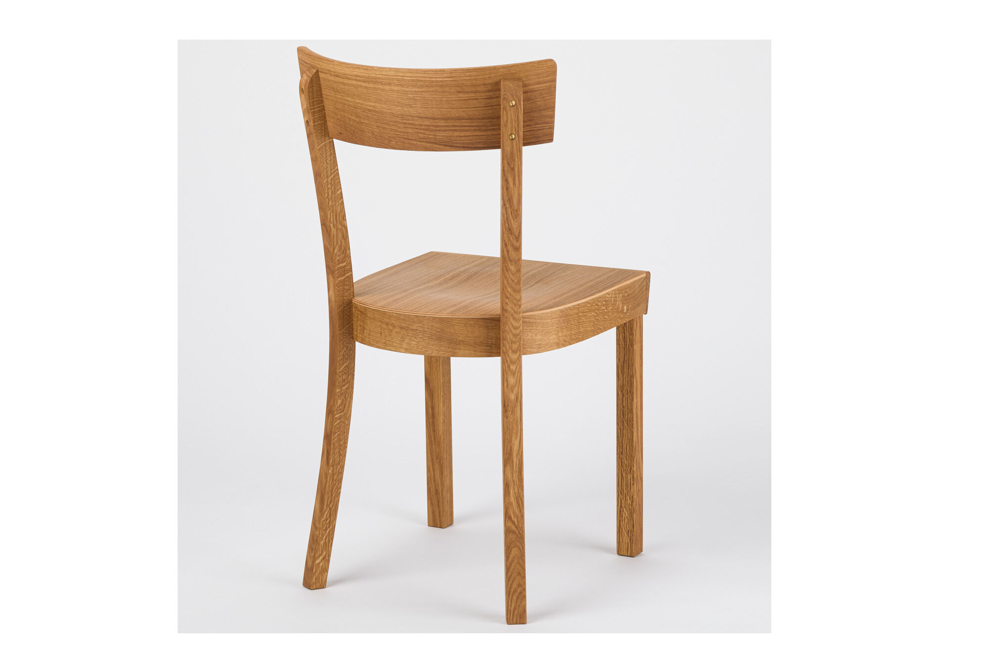 Ein Frankfurter Küchenstuhl aus massiver, geölter Eiche steht vor neutral hellem Hintergrund. Der Stuhl hat eine geschwungene Rückenlehne und eine einfache, klassische Form. Ideal für Küche oder Esszimmer und traditionelles, minimalistisches Wohnambiente.