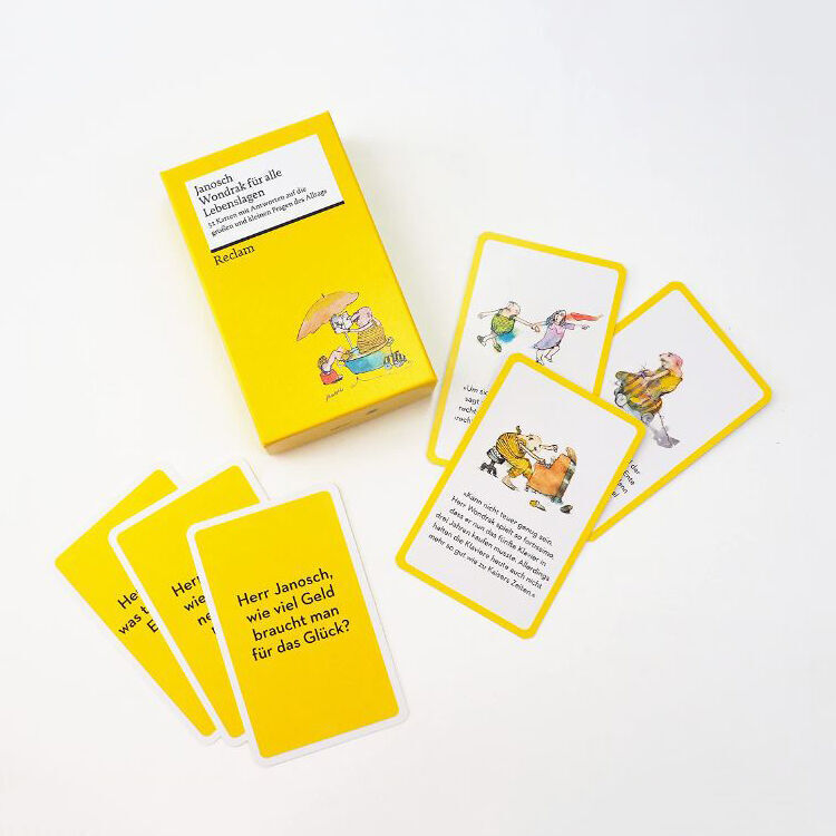 Die Kartenbox Janosch: »Wondrak für alle Lebenslagen« zeigt ein gelbes Kartenset mit humorvollen Illustrationen und Weisheiten von Janosch. Auf einigen Karten sind bunte Bilder und Texte zu sehen, die alltägliche Situationen humorvoll kommentieren.