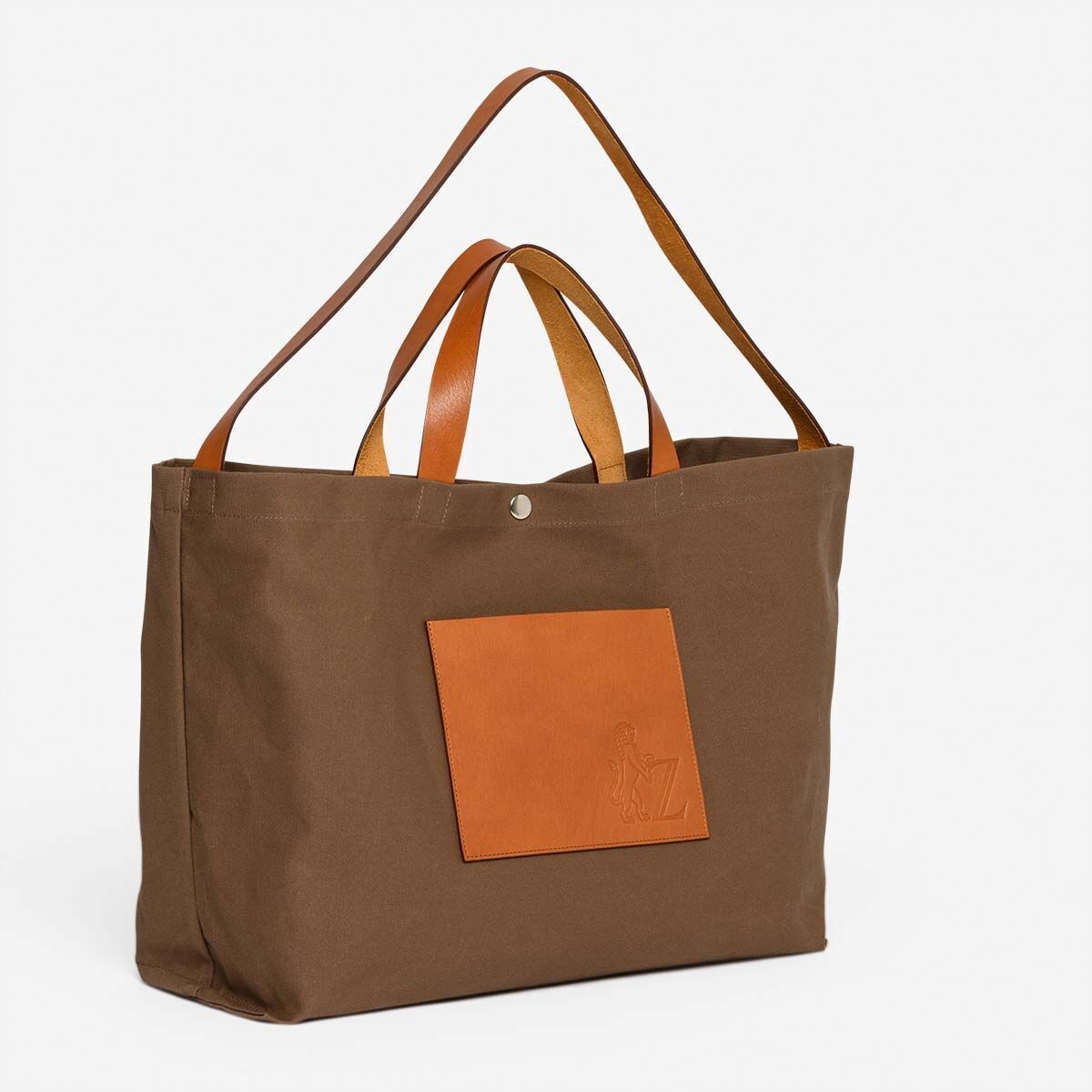 Braune Jubiläums-Markttasche mit Lederhenkeln und bequemen Griffen. Die Tasche hat ein großes Fach auf der Vorderseite und ist geräumig, ideal für den Alltag und den Einkauf.